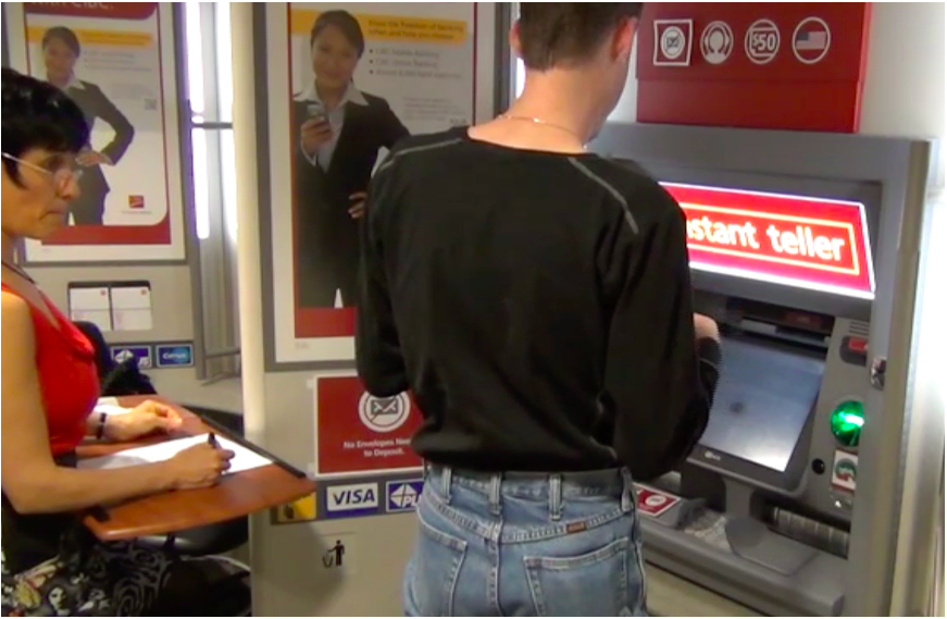 Ilona Posner conducting Usability Test of an ATM Machine with a male user (wearing dark clothes) and looking at the bank machine.