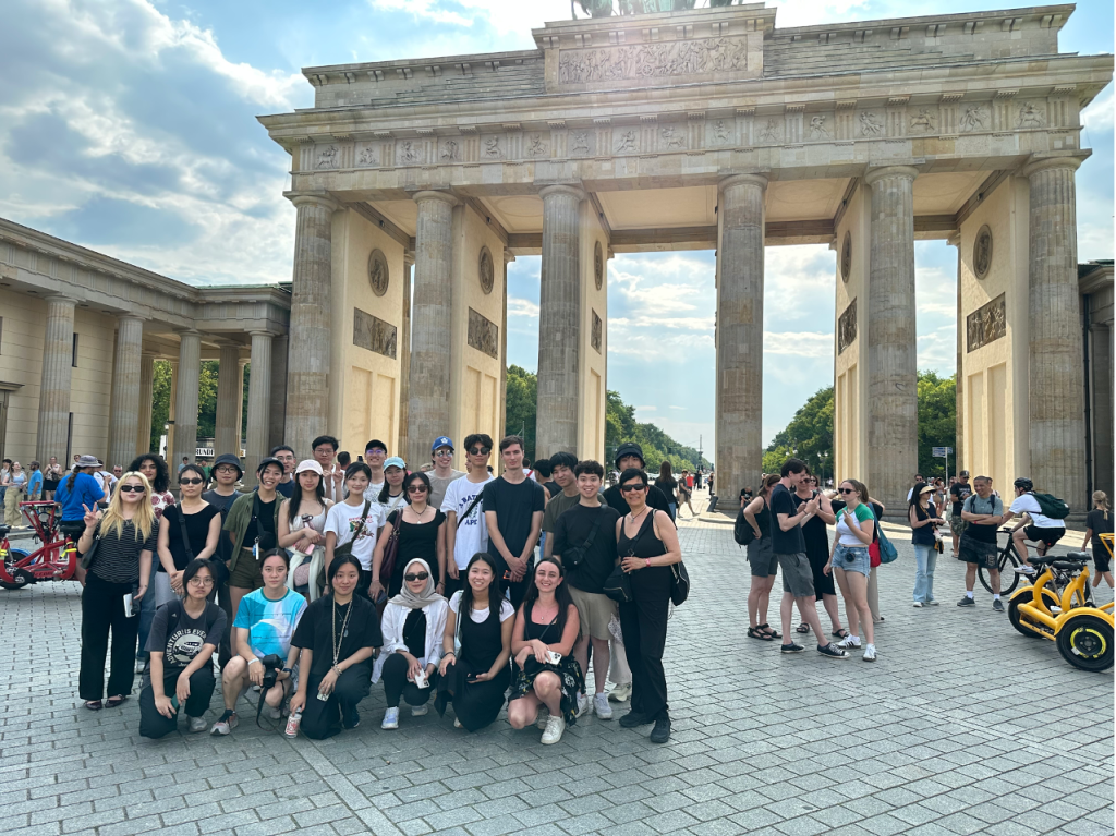 Photo of the class of CSC396 with ILONA POSNER and 23 students posing at the Brandenburg Gate in Berlin, Germany, July 2025