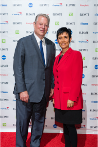 Photo of Al Gore (wearing a grey suit) and Ilona Posner (wearing a red blazer and black skirt), taken at the Elevate Conference in 2018.